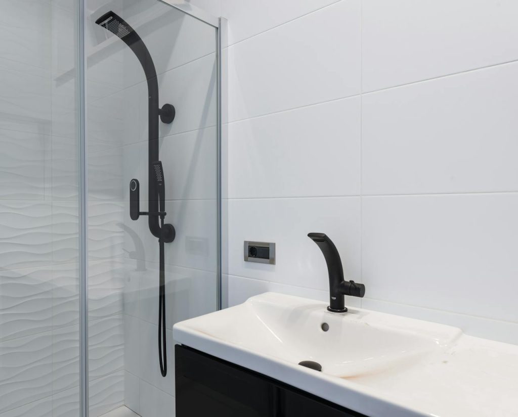 Minimalist bathroom featuring black sink and shower fixtures with white tiles.